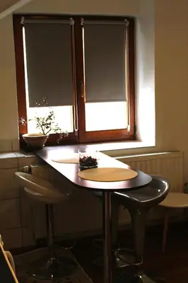 a table and two stools in front of a window at Svila Apartmani in Bihać