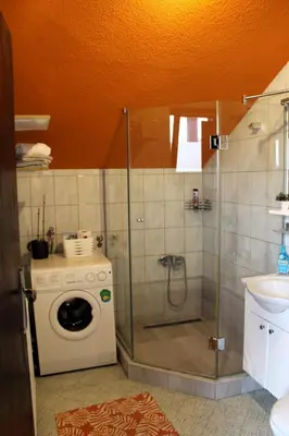 a bathroom with a shower and a washing machine at Svila Apartmani in Bihać
