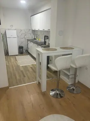 a kitchen with a white table and two bar stools at Apartman Aura in Travnik