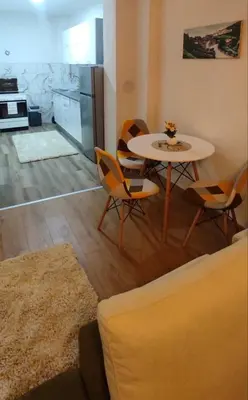 a living room with a table and chairs and a kitchen at Apartman Aurora in Travnik