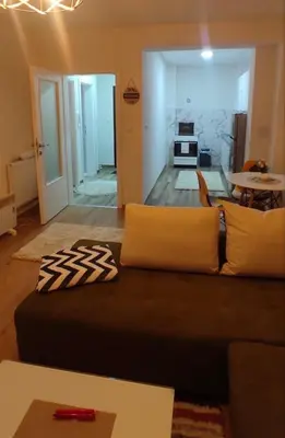 a living room with a couch and a kitchen at Apartman Aurora in Travnik