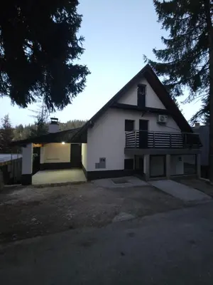 a white house with a porch and a garage at Vila Flora Vlašić in Šišava