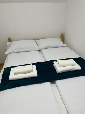 a bed with two white pillows and two towels at Vila Flora Vlašić in Šišava
