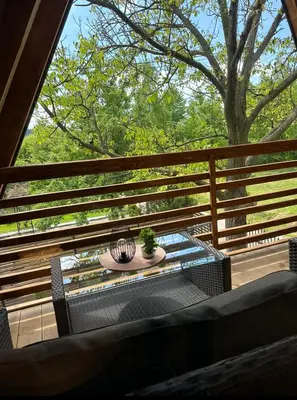 a table and chairs on a balcony with a tree at Ammirevole Ravne Oga in Visoko