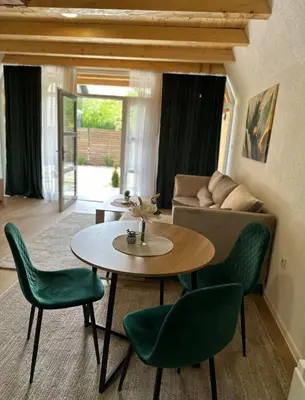 a living room with a table and green chairs at Ammirevole Ravne Oga in Visoko