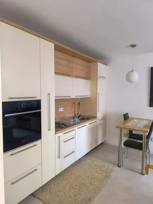 a kitchen with white cabinets and a wooden table at Esma in Bihać