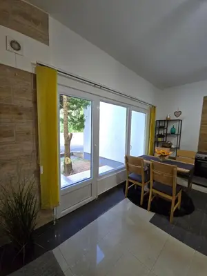 a living room with a table and a large window at Riverstone Retreat in Jajce