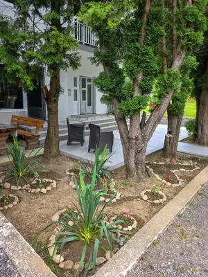a garden with two benches and trees in front of a house at Riverstone Retreat in Jajce