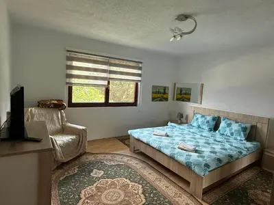 a bedroom with a bed and a chair and a window at Comfort house near pyramides in Visoko