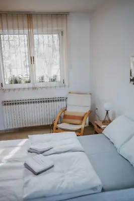 a bedroom with two beds and a chair and a window at MASAL Studio Apartman in Bihać