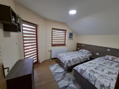 a bedroom with two beds and a table and windows at Djuric Vacation House in Laktaši