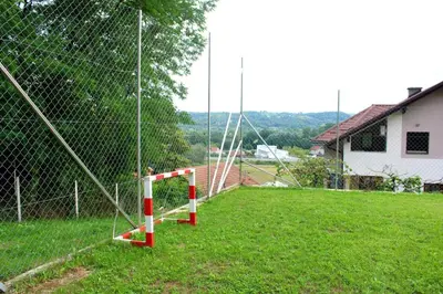 a fence with red and white poles in a field at Djuric Vacation House in Laktaši