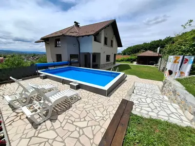 a swimming pool with chairs and a house at Djuric Vacation House in Laktaši