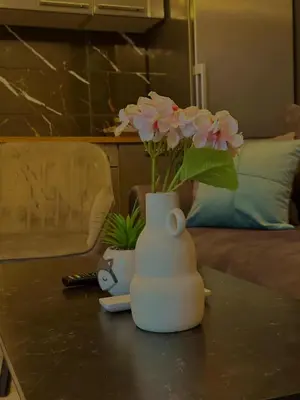 a white vase with pink flowers on a table at Apartman Fin in Jajce