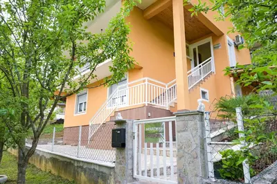 a yellow house with a white fence and a porch at Palma in Jajce