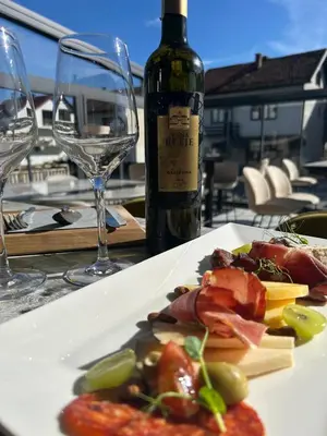 a white plate of food and a bottle of wine at CASA V BENCUN Deluxe Queen Rooms in Kiseljak