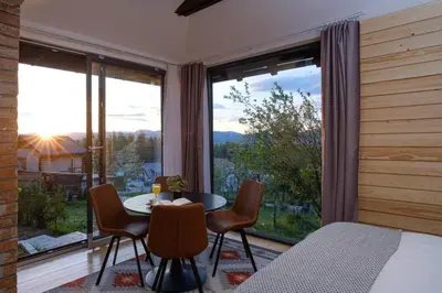 a bedroom with a table and chairs and a large window at BLOK- Brick and wood cottage in Visoko