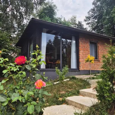 a small brick house with a window and flowers at BLOK- Brick and wood cottage in Visoko