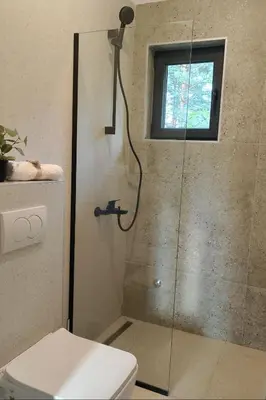 a bathroom with a shower with a toilet and a window at BLOK- Brick and wood cottage in Visoko