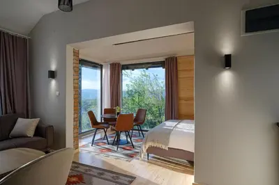 a bedroom with a bed and a table and chairs at BLOK- Brick and wood cottage in Visoko