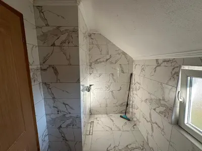 a bathroom with a shower with white marble tiles at Stan na dan Banjaluka in Banja Luka