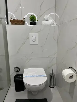 a white bathroom with a toilet and towels at Apartments Indigo in Jajce