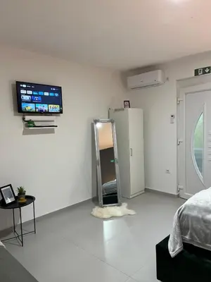 a white room with a bed and a tv on the wall at Apartments Indigo in Jajce