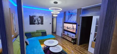 a living room with a blue couch and a television at Smart Lux in Tuzla