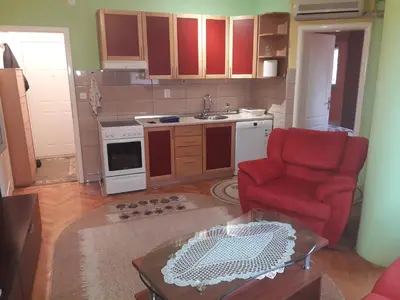 a living room with a red chair and a kitchen at Kiki in Banja Luka