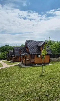 a row of wooden houses with a grass yard at Suncev Brijeg in Banja Luka