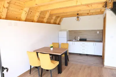 a kitchen and dining room with a wooden table and yellow chairs at Bungalov Mila in Šipovo