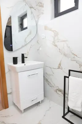 a white bathroom with a sink and a mirror at Bungalov Mila in Šipovo