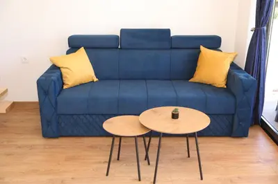 a blue couch with two tables in a living room at Bungalov La Repit in Šipovo