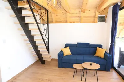 a living room with a blue couch and stairs at Bungalov La Repit in Šipovo