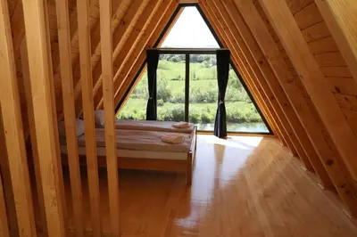 a attic room with a bed and a large window at Bungalov La Repit in Šipovo