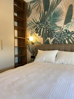 a bedroom with a bed with a tropical wallpaper at Green Lux Apartman Prijedor in Prijedor