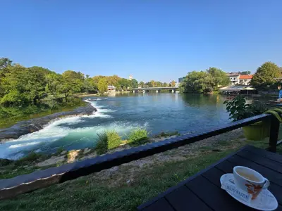 a cup of coffee sitting on a table next to a river at The Urbanite in Bihać
