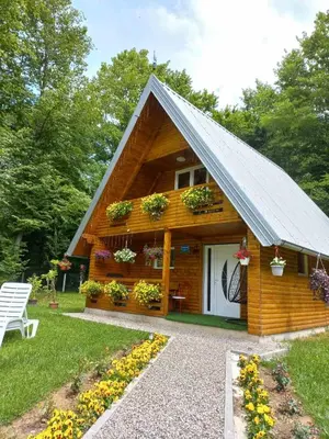 a log cabin with flowers in front of it at Vikendica Anastasija in Laktaši