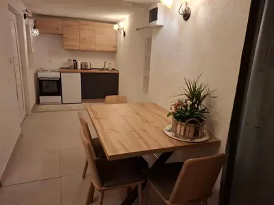 a kitchen and dining room with a wooden table and chairs at Delux Apartmans in Kulen Vakuf