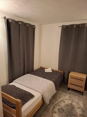 a small bedroom with a bed and a table at Delux Apartmans in Kulen Vakuf