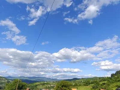 a kite flying in a blue sky with clouds at Visoko Pyramid VALLEY in Visoko