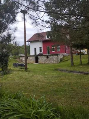 a red and white house in a yard with trees at Villa Janj in Šipovo