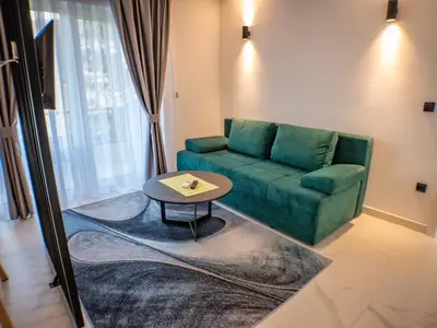 a living room with a green couch and a table at Sunny Corner Apartments in Visoko