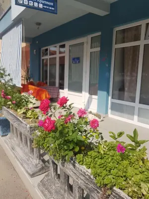 a retaining wall with pink flowers in front of a house at Adnna Home in Bihać