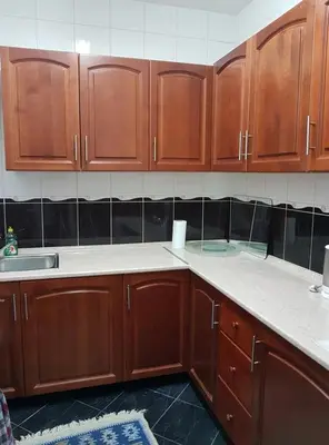 a kitchen with wooden cabinets and white counter tops at Adnna Home in Bihać