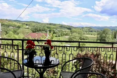 a table with chairs and flowers on a balcony at Green River Rooms in Šipovo