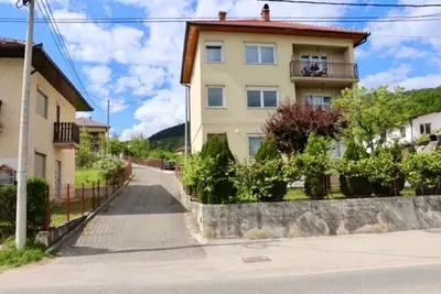 a house on a street next to a building at Green River Rooms in Šipovo