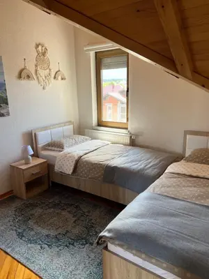 two beds in a room with a window at Teal Apartment 3 in Bihać