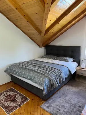 a bed in a room with a wooden ceiling at Teal Apartment 3 in Bihać