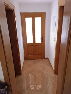 a hallway with a wooden door and a window at Apartman EMA in Kulen Vakuf